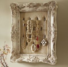 an ornate white frame with jewelry hanging on it