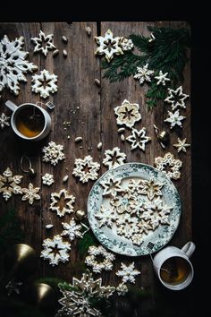 a table topped with plates and cups filled with food next to snowflakes