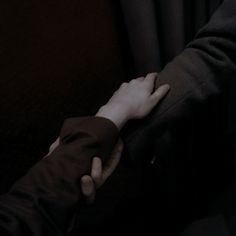 two people holding hands while sitting on a bus in the dark with their arms wrapped around each other