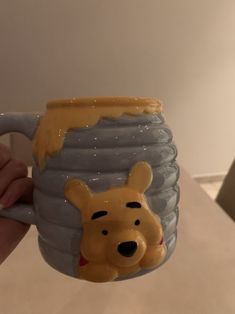 a winnie the pooh mug is being held up to show it's face