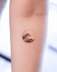 a woman's arm with a small wave tattoo on it