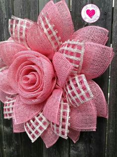 a pink flower on top of a wooden fence