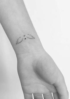 a small tattoo on the wrist of a woman's hand, with two leaves