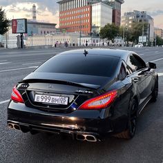 a black mercedes cls parked on the side of the road in front of some buildings