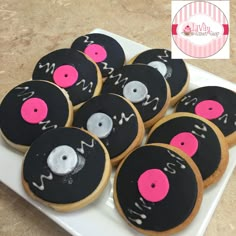 decorated cookies with pink and black icing on a white plate