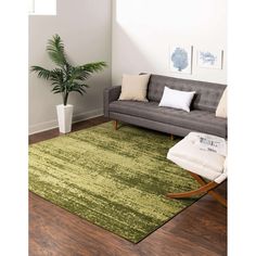 a living room with a couch, chair and rug on the wooden floor next to a potted plant