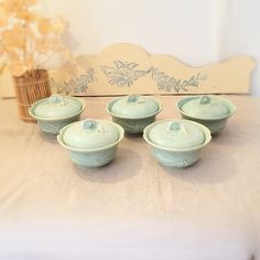 four green bowls sitting on top of a white table