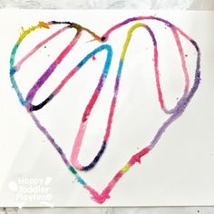 a heart made out of colored crayons on top of a piece of paper