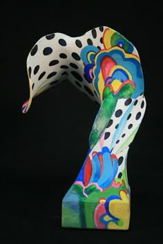 a colorful sculpture is shown on a black background with polka dots and spots in the shape of a bird