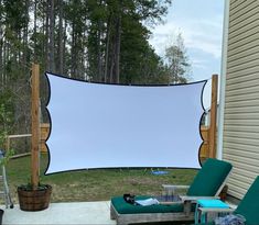 a large white screen sitting in the middle of a yard next to two lawn chairs