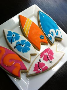 decorated cookies are arranged on a plate with flowers and surfboards in the shape of waves