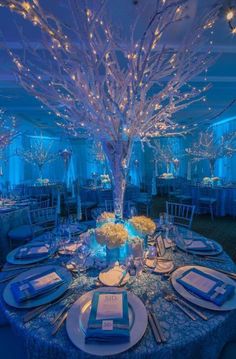 the table is set with blue linens, silverware and white place settings for an elegant dinner