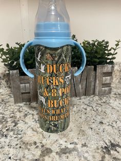 a blue sippy cup sitting on top of a counter next to a potted plant