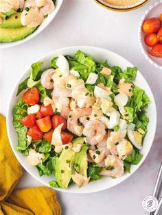 a salad with shrimp, avocado and tomatoes on the side is ready to be eaten