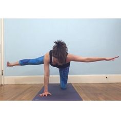 a woman is doing yoga on a mat in front of a blue wall and hardwood floor