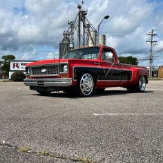 an old red truck parked in a parking lot