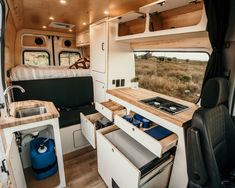 the interior of a camper with an oven, sink and stove top in it