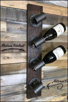 three bottles of wine are hanging on a wooden wall with two metal holders and one is holding the same bottle