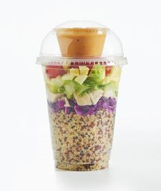 a salad in a plastic container with a lid on it, sitting on a white surface