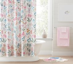 a white bath tub sitting next to a window covered in pink and blue shower curtains