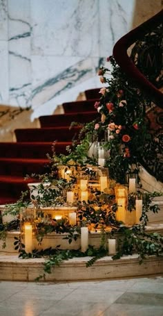 candles are lit in front of a staircase decorated with flowers and greenery on the steps