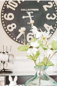 a vase filled with white flowers sitting on top of a table next to a clock