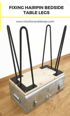 a metal suitcase sitting on top of a hard wood floor next to two black handles