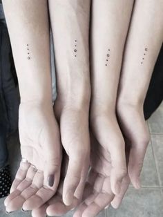 three people are holding their hands together with small dots on the wrist and fingers above them