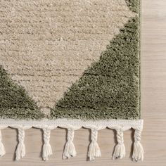 an area rug with tassels on top of it and a wooden floor in the background