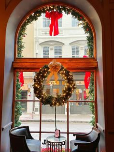 a wreath is hanging on the window sill in front of two chairs and a table