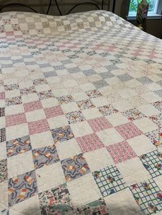 a bed with a quilt on top of it in a room next to a window