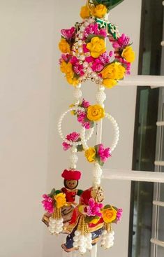 a wind chime with flowers hanging from it's side on a table next to a window