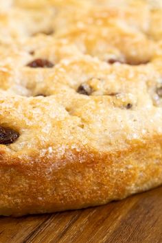 a close up of a cake on a wooden table with white frosting and raisins