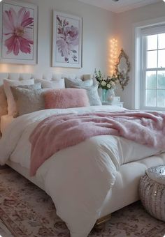 a white bed with pink pillows and blankets