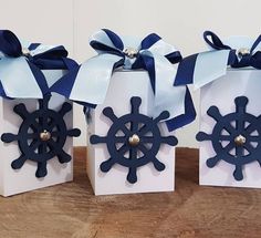 three small boxes with blue ribbons and bows on them are sitting on a wooden table