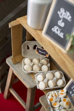 several trays of eggs sitting on top of a wooden table next to a chalkboard