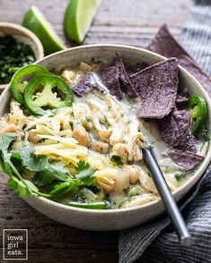 a bowl of soup with tortilla chips and avocado on the side