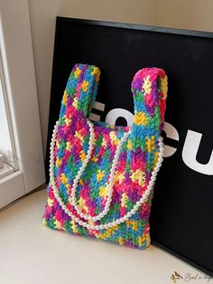 a crocheted purse sitting on top of a table next to a black sign