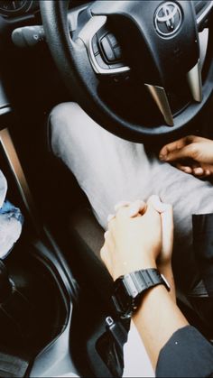 a person is sitting in a car with their hand on the steering wheel while holding onto his wrist