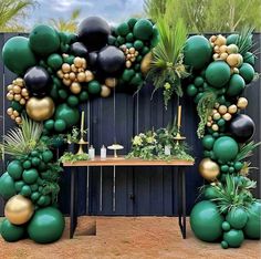 a table topped with lots of green and gold balloons