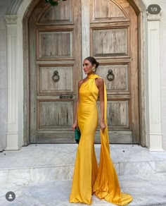 a woman standing in front of a door wearing a yellow dress