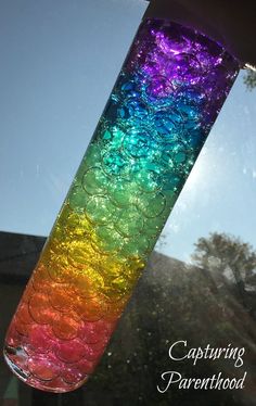 a colorful glass vase sitting on top of a window sill next to a tree