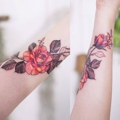 two tattoos with flowers and leaves on their arms, one has a red rose in the middle