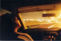 a man driving down a highway at night with his head up in the drivers seat