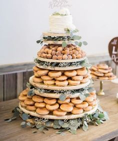 a wedding cake made out of doughnuts and greenery on a wooden table