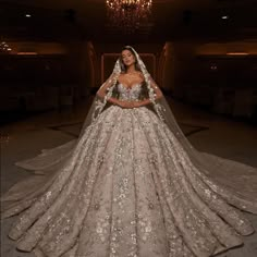 a woman in a wedding dress standing next to a chandelier with lights on it