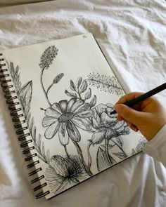 a person is drawing flowers on a notebook