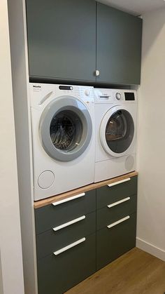 a washer and dryer are in the corner of a room with cabinets on either side