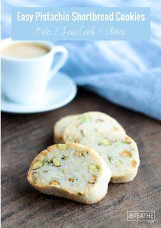 three pistachio shortbread cookies on a wooden table next to a cup of coffee