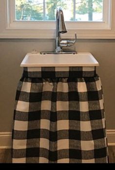 a kitchen sink with a black and white checkered table cloth on it's bottom